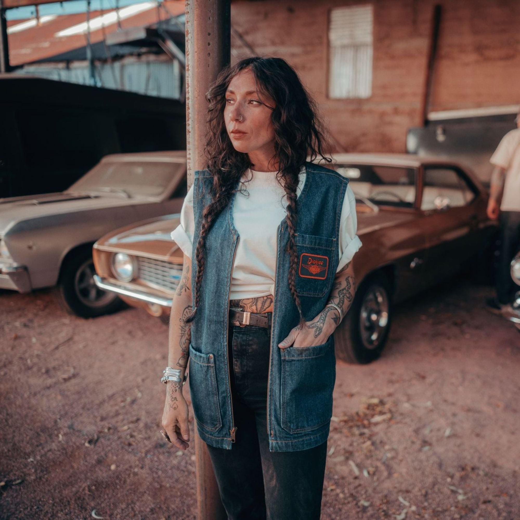 Person wearing Hdxdickies Denim Lined Vest RNB Vest Vest, Vintage automotive garage with classic cars and industrial brick