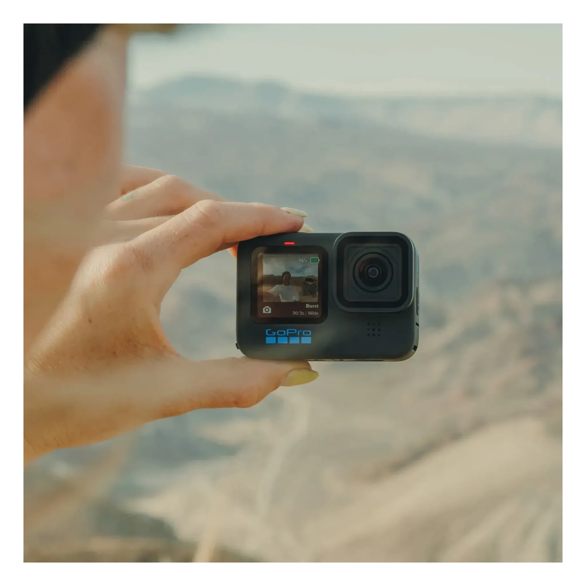 Person wearing Hero 11 Camera Black Camera, Hand holding compact action camera above mountainous landscape vista - Slowride