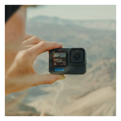 Person wearing Hero 11 Camera Black Camera, Hand holding compact action camera above mountainous landscape vista - Slowride