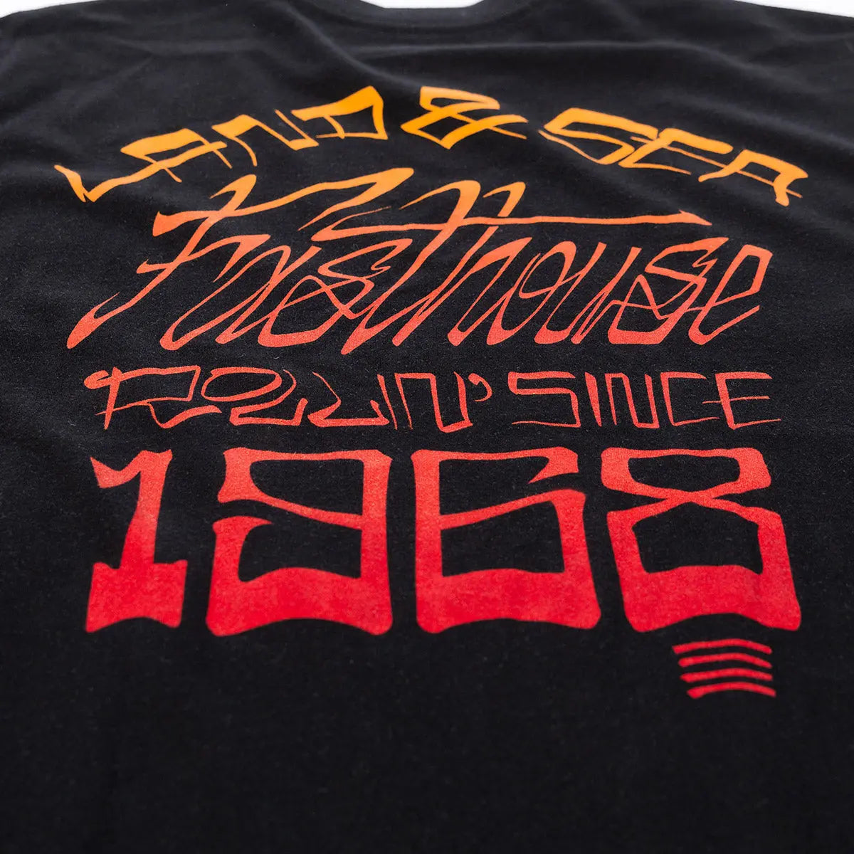 Close-up of Horizon Black Tee showing Print texture showing layered orange to red gradient lettering with racing-themed