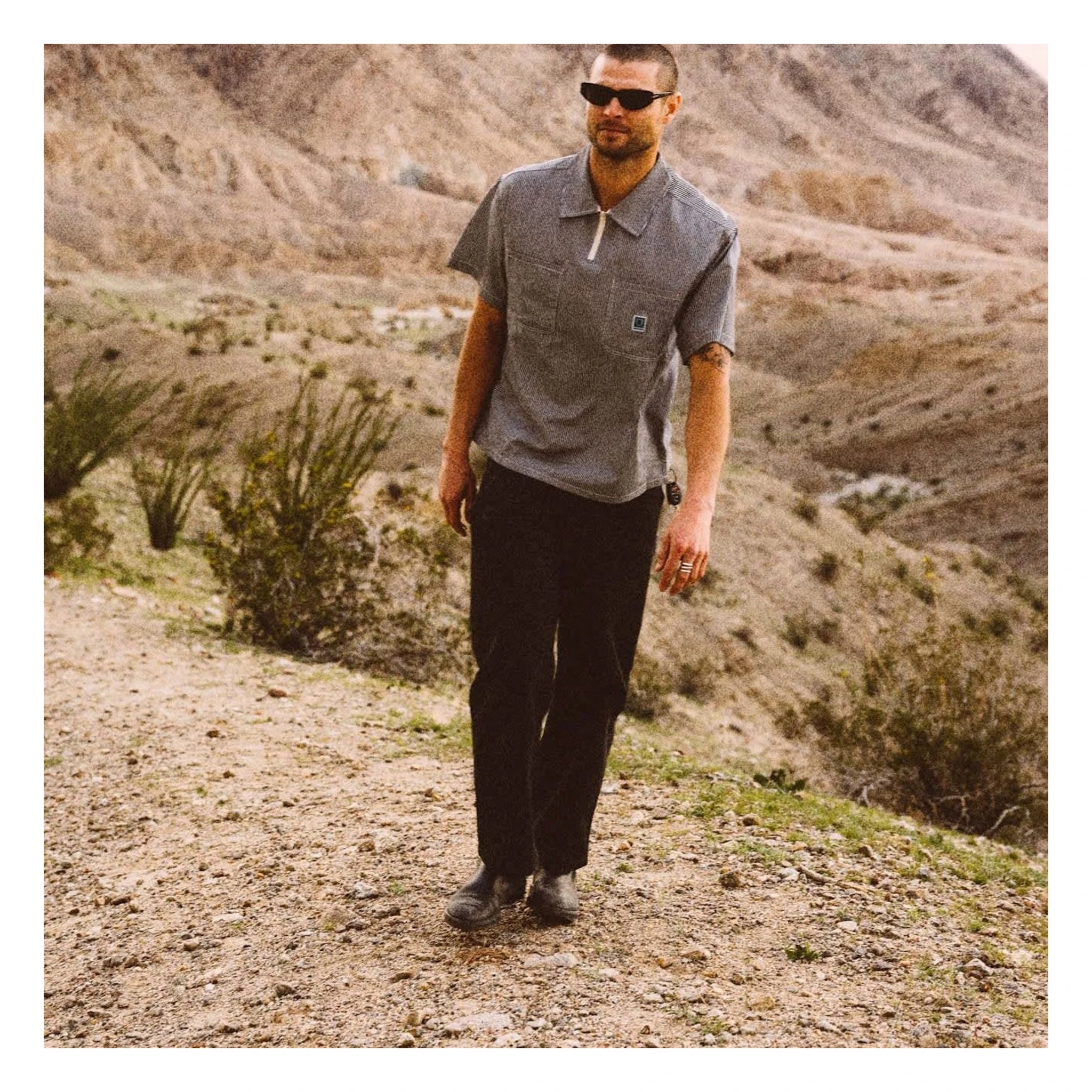 Person wearing Journey LW SS Woven Navy/white Stripe S/S Woven S/S Woven, Man in grey polo shirt standing on desert dirt
