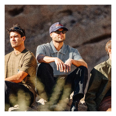 Person wearing Journey LW SS Woven Navy/white Stripe S/S Woven S/S Woven, Men seated outdoors against textured concrete wall