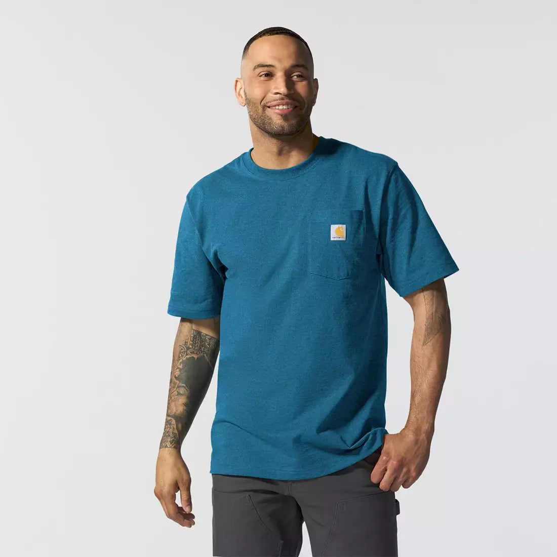 Person wearing K87 (reg) Black Tee, Man wearing teal t-shirt standing against neutral studio background - Slowride Supply