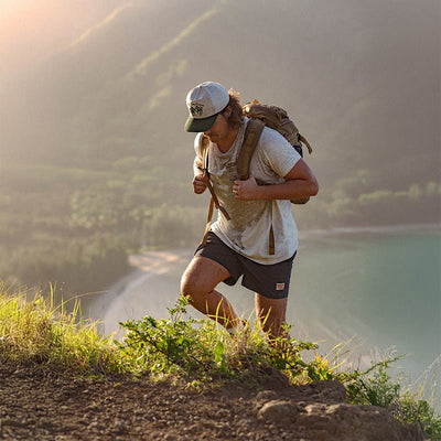 Person wearing Los Rios Cordouroy Snapback Cream/green Hat, Runner jogging on mountain ridge overlooking turquoise alpine