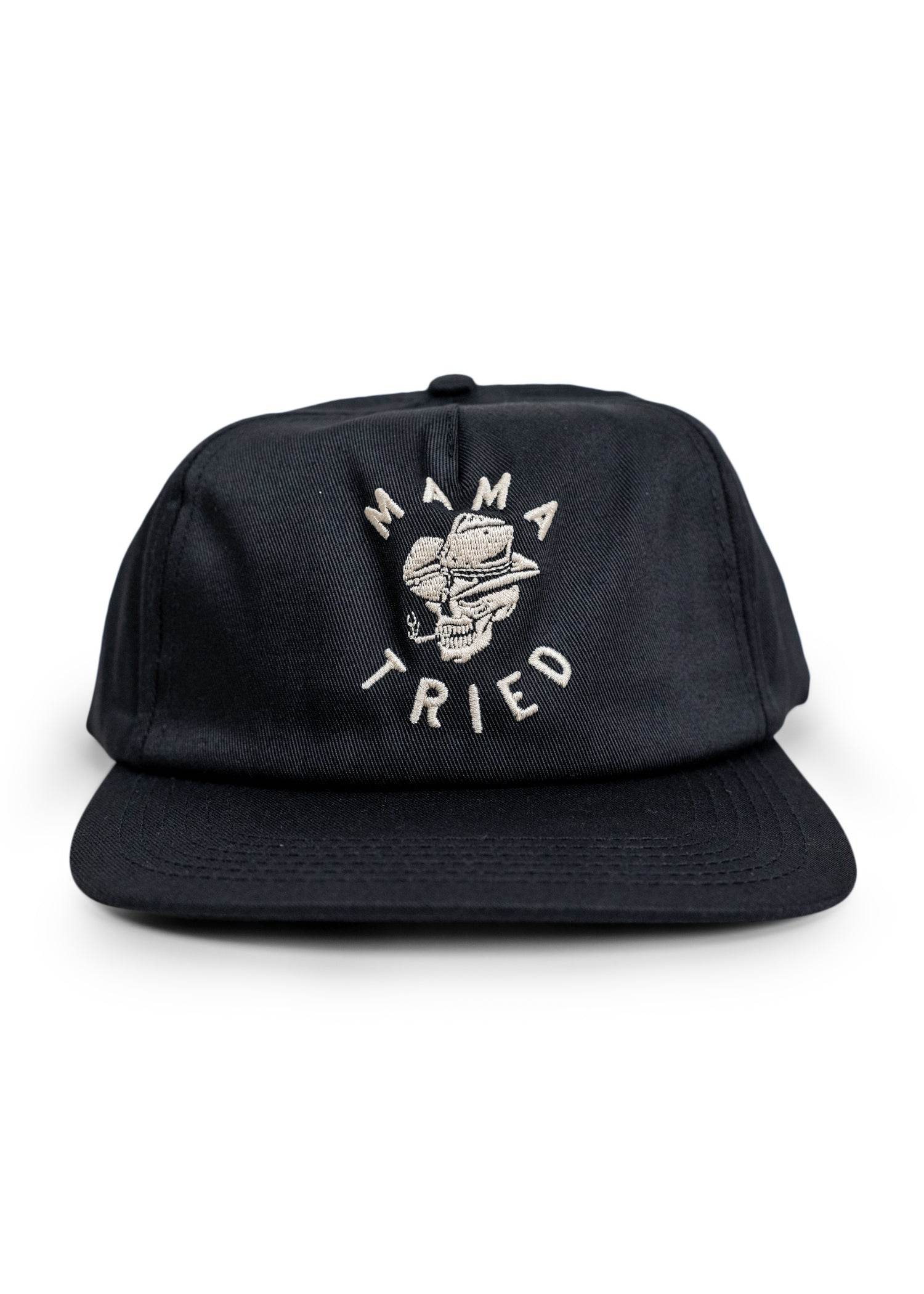 Mama Tried front view, Black snapback with cream embroidered skull and crossed wrenches graphic, text arranged in circle