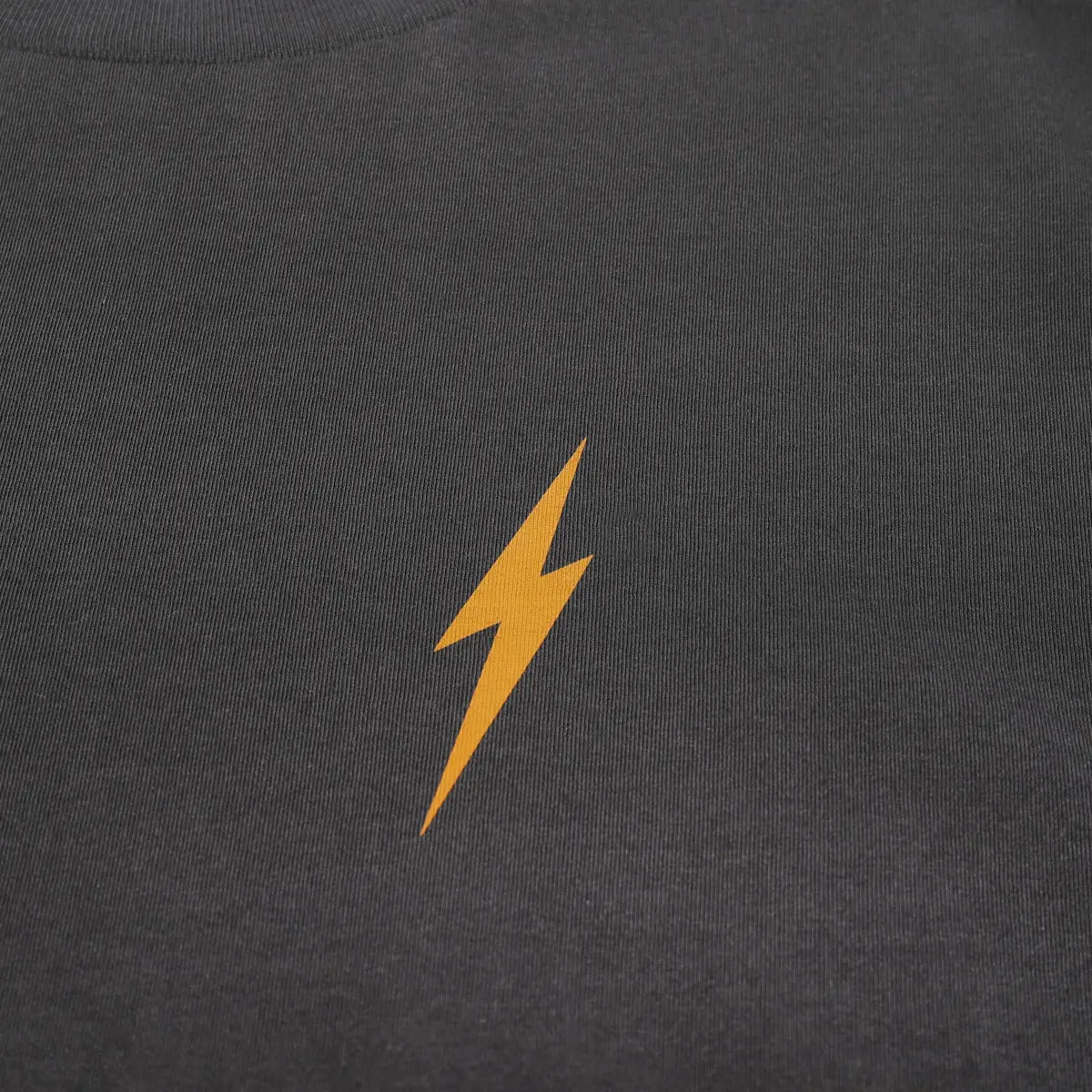 Close-up of Manasa Graphite Black Tee showing Gold lightning bolt embroidered on ribbed charcoal fabric - Slowride Supply