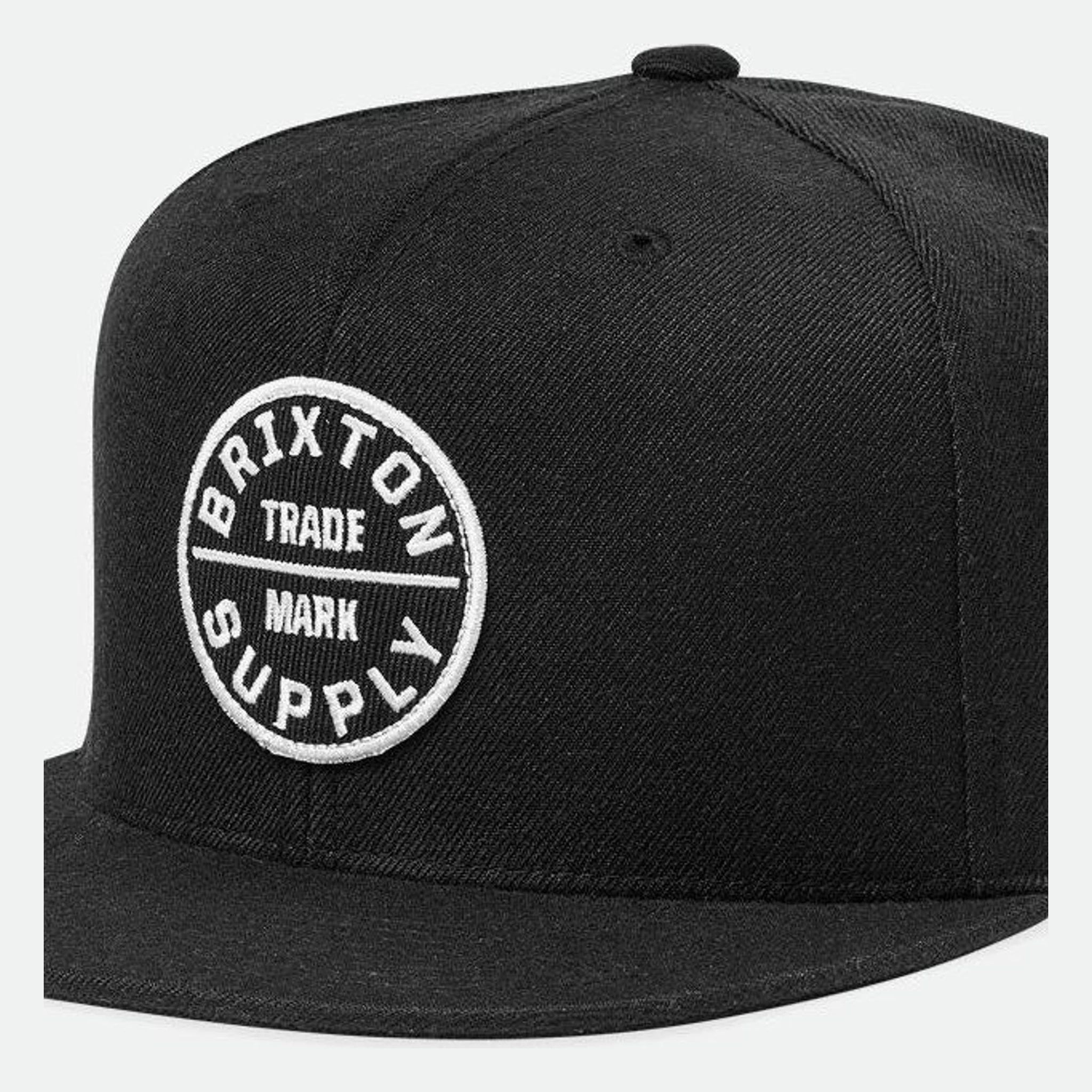 Oath III Snapback front view, Black with white circular trade mark emblem and horizontal dividing line on front panel,