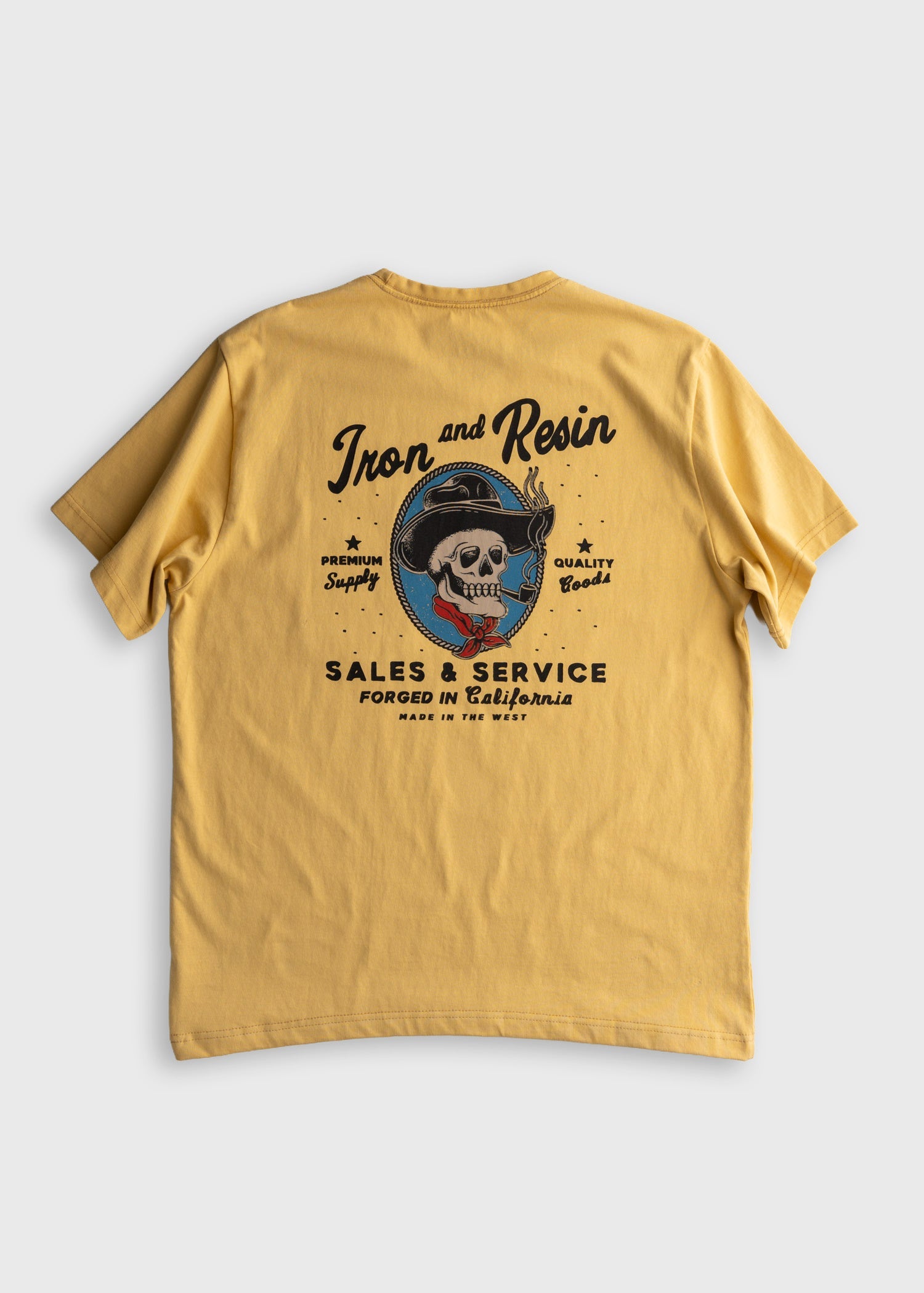 Back of Old Cowboy Pocket Black Tee, Gold with black script "Iron and Resin" text, skull in blue circle wearing cowboy hat,