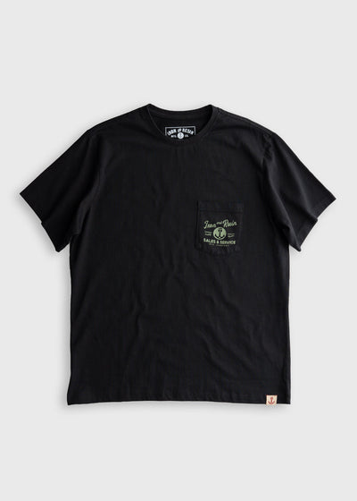 Close-up of Old Cowboy Pocket Black Tee showing Black cotton tee with chest pocket print featuring circular badge and "Sales