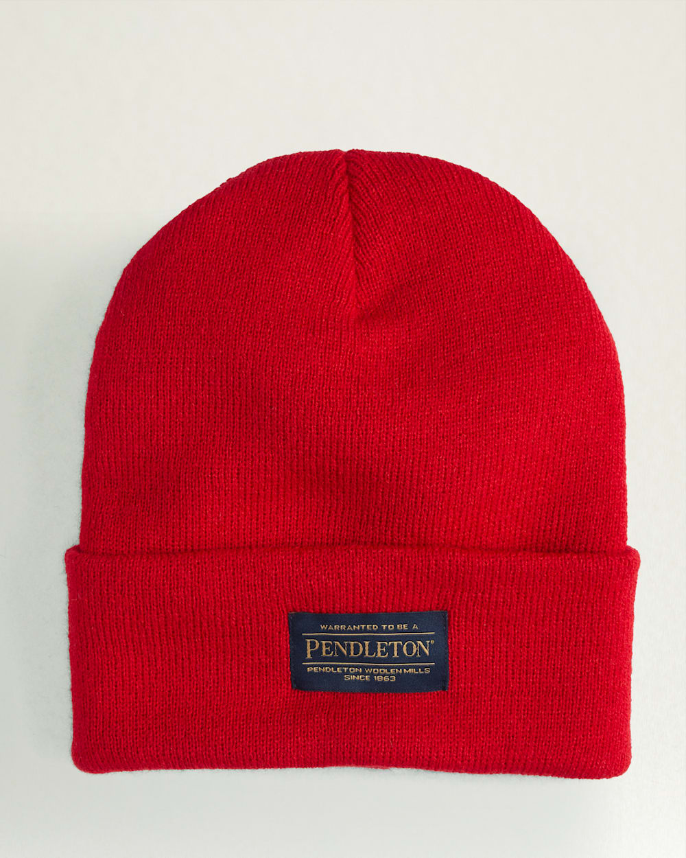 front view, Bright red knit beanie with dark woven label at cuff reading "Warranted to be a Pendleton" and "Pendleton Woolen