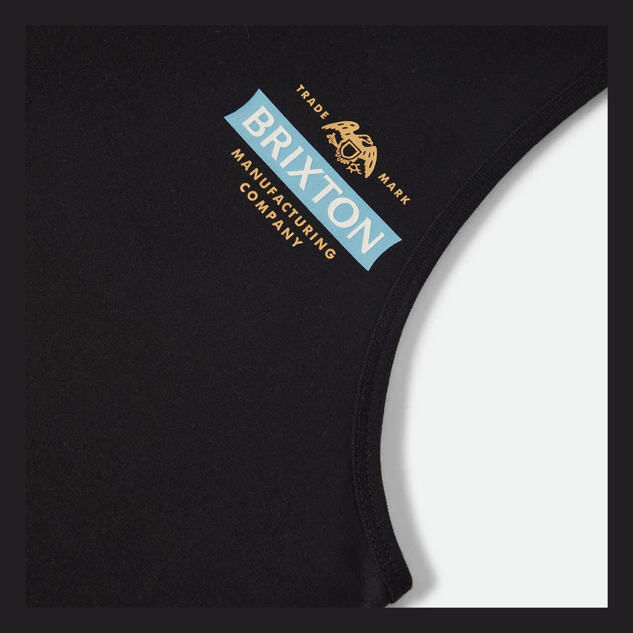 Close-up of Pinnacle Tank Top Apparel Black Apparel showing Light blue rectangular patch with white lettering, gold text and