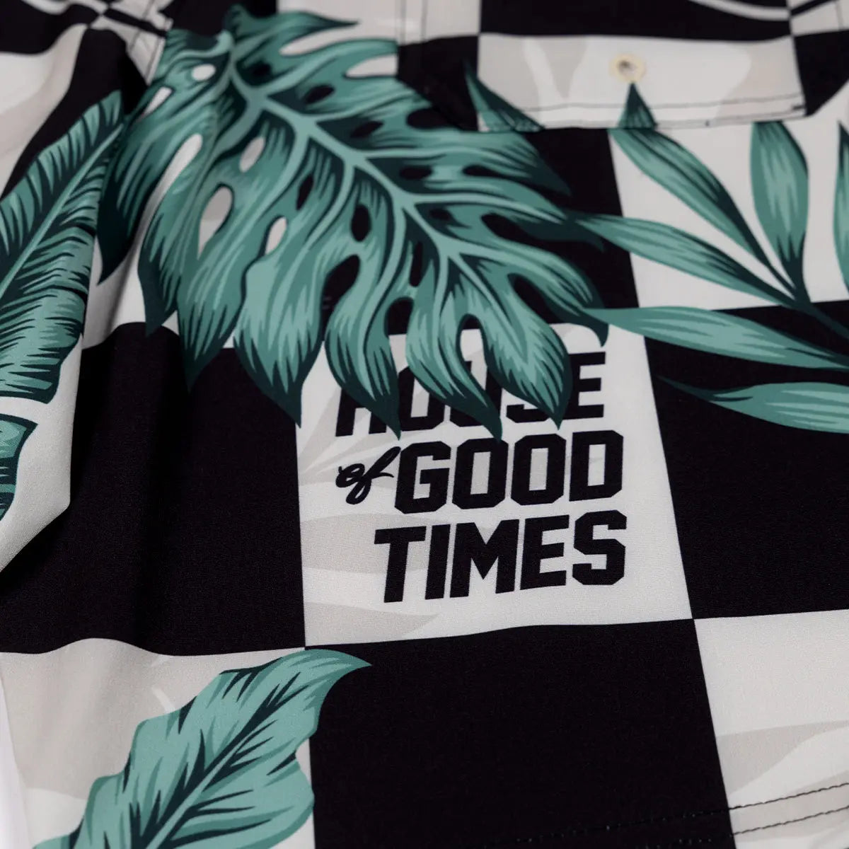 Close-up of Poolside 19" Boardshort Apparel Black/Off White Apparel showing Teal monstera leaf print with black text reading