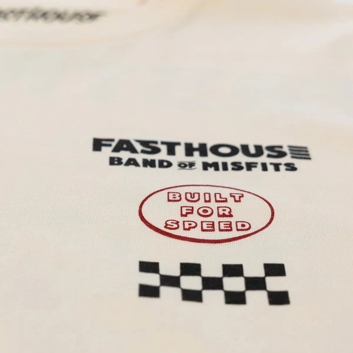 Close-up of Pursuit Natural Tee showing Black text reading "FASTHOUSE BAND OF MISFITS" with red oval stamp "BUILT FOR SPEED"