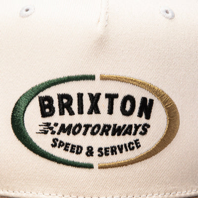Close-up of Rhett MP Snapback Off White/pinecone Brown Hat showing Embroidered oval logo with green and gold border, black