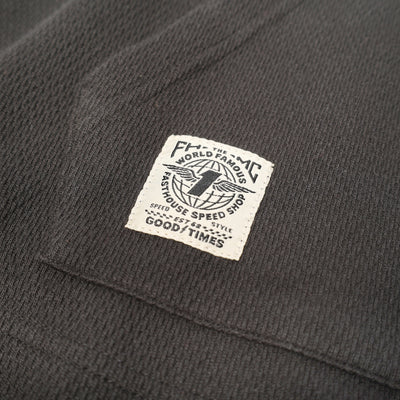 Care label on Robin Hooded Thermal Apparel Black Apparel showing Cream woven label with black text and globe graphic,