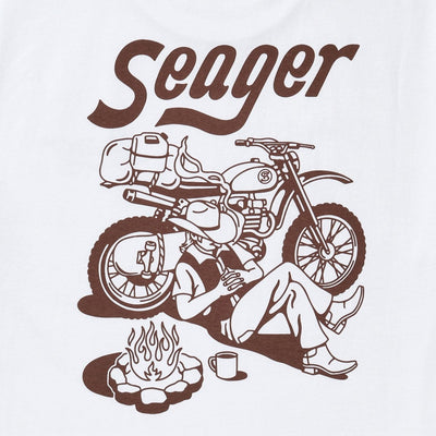 Close-up of Romero White Tee showing Brown italic serif lettering and line-art motorcycle graphic with campfire scene detail