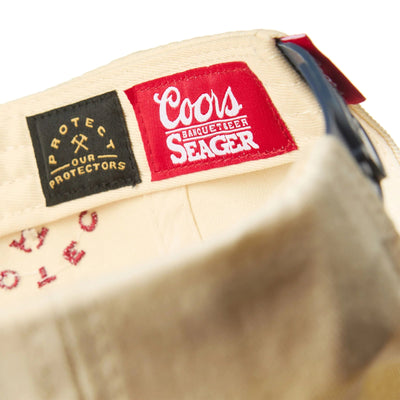 Care label on X Coors Banquet P.o.p. Snapback Cream/navy-cream/navy Hat showing Woven red label with white script logo and