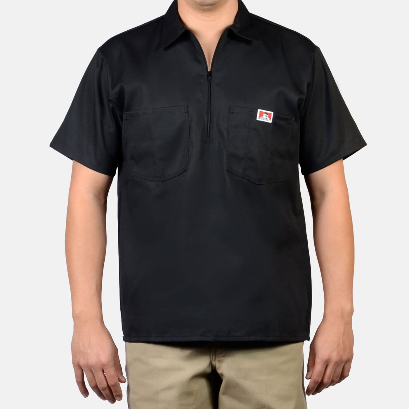 Short Sleeve Solid Half Zip S/S Woven front view, Black with small red and white badge on chest pocket, half-zip collar and