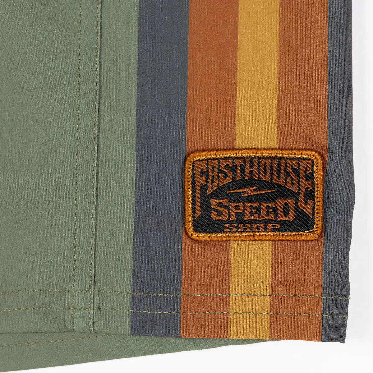 Close-up of Skeg 21" Boardshorts Apparel Olive Apparel showing Embroidered patch with orange border and black text reading