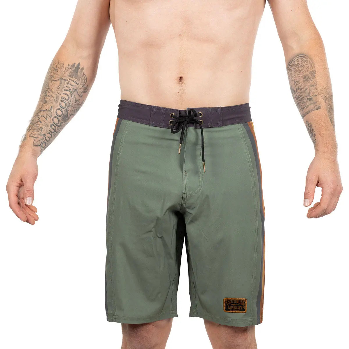 Person wearing Skeg 21" Boardshorts Apparel Olive Apparel, Shirtless male model wearing olive boardshorts against plain