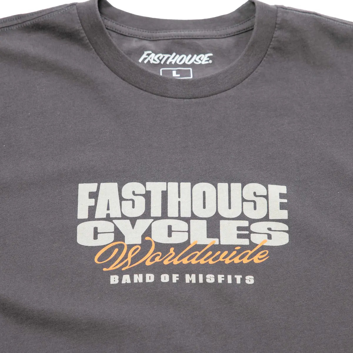 Close-up of Spanner Mirage Gray Tee showing Mirage gray with white and gold screenprint reading "Fasthouse Cycles Worldwide