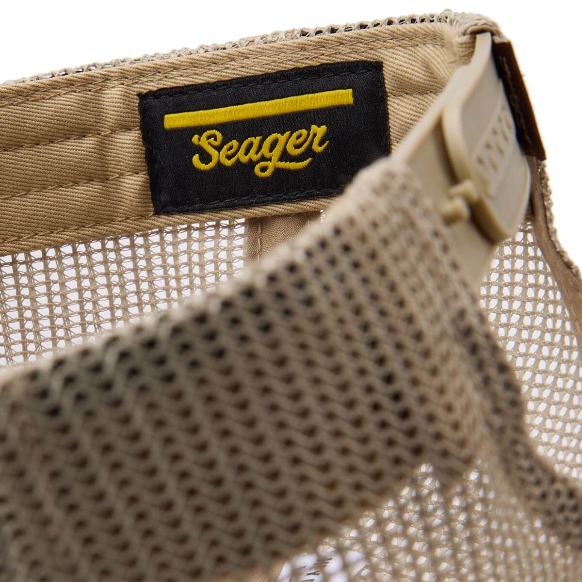 Care label on The Herd Trucker Army Green Hat showing Black woven label with yellow script text and stripe detail - Slowride
