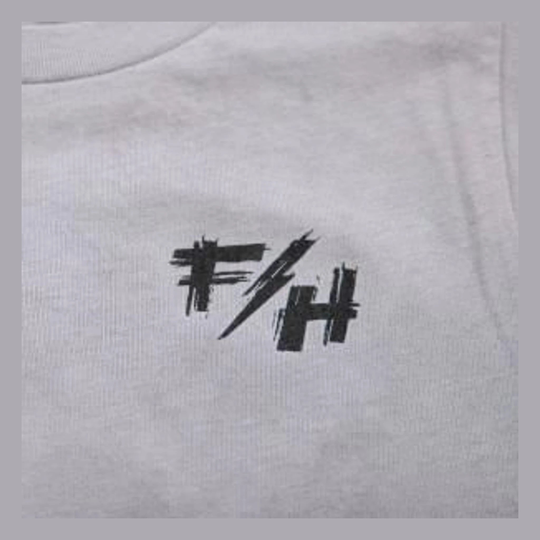 Close-up of Toddler Fray Tee Kids Light Gray Kids Tee showing Black hand-drawn graphic print with abstract angular marks and