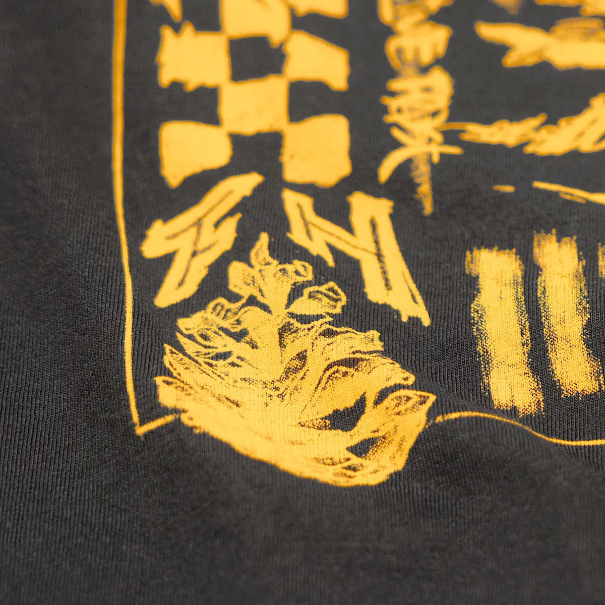 Close-up of Tomahawk Natural Tee showing Yellow screen-printed graphic detail with textured halftone shading on charcoal