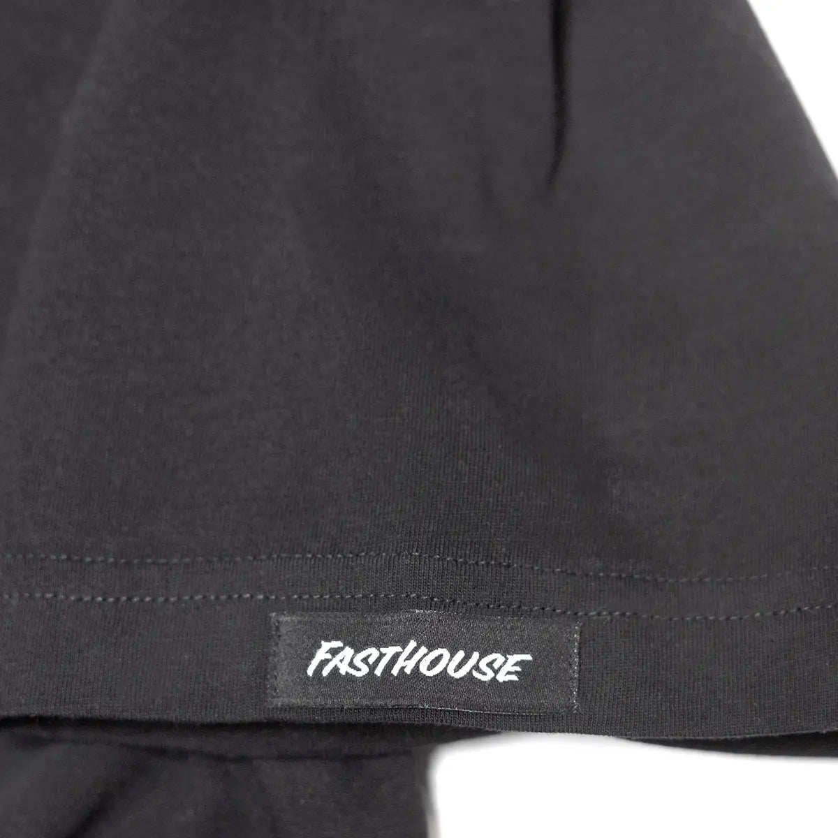 Close-up of Tomahawk Natural Tee showing White embroidered text on black woven label sewn into hem - Slowride Supply