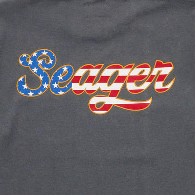 Close-up of USA Russ Vintage Black Tee showing Embroidered script logo with blue star-filled S, red and white striped