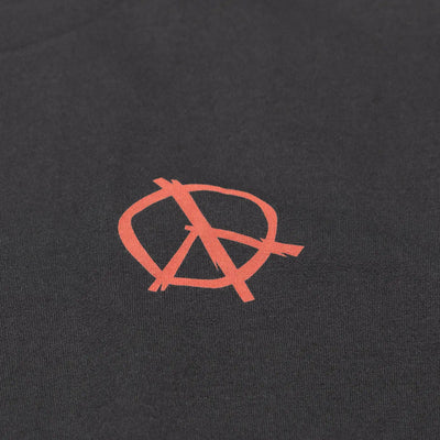 Close-up of Utopia Black Tee showing Coral anarchy symbol embroidered on charcoal fabric with visible stitch texture -
