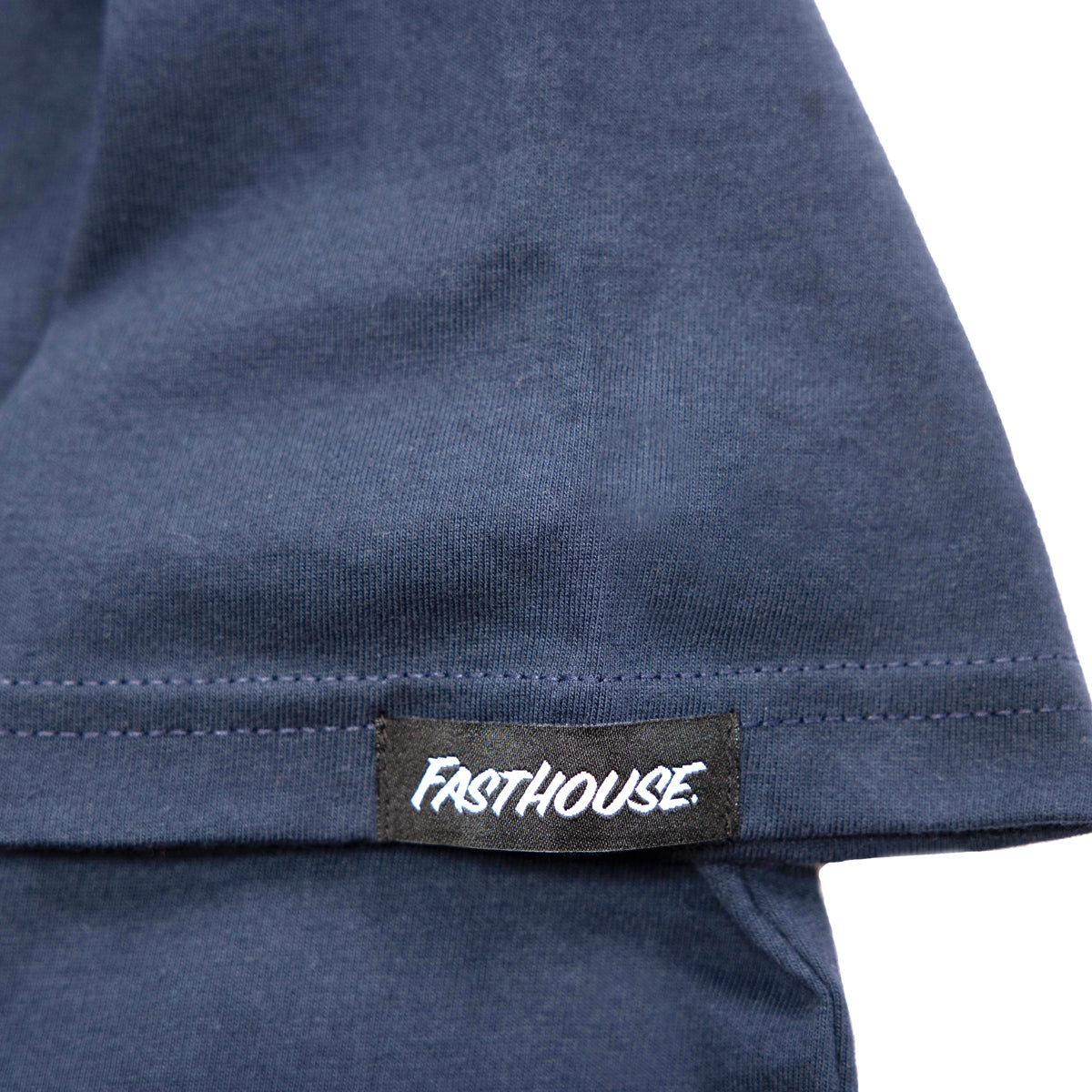 Close-up of Youth Spanner Tee Kids Midnight Navy Kids Tee showing Black woven label with white italic script text on navy