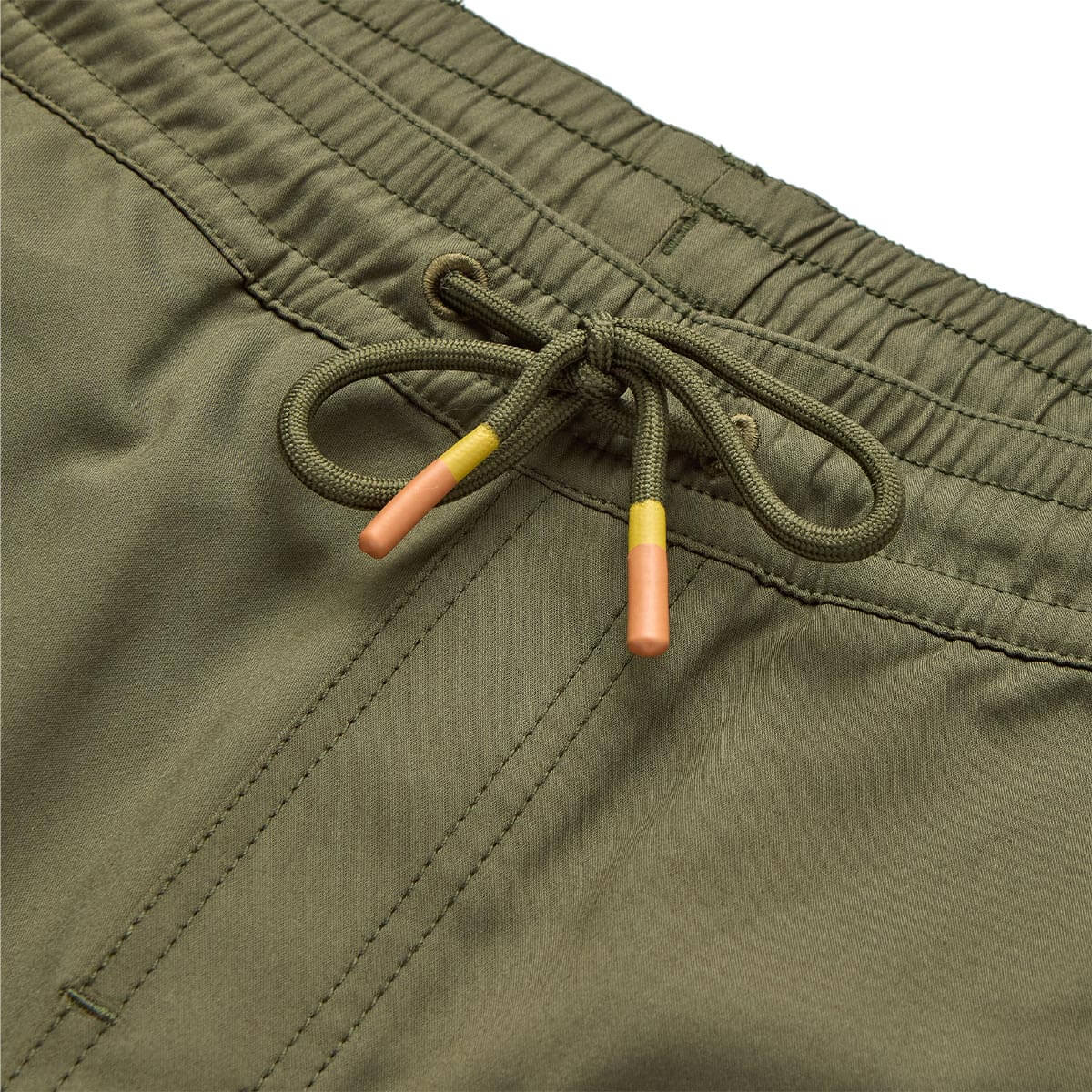 Close-up of Yuma Shorts Dark Olive Shorts showing Drawstring waistband with olive cord and coral-yellow tipped aglets,